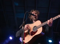 a man holding an acoustic guitar and singing into a microphone