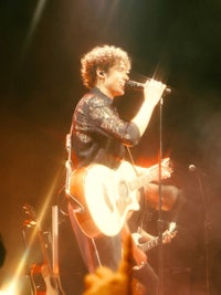 a man on stage with an acoustic guitar