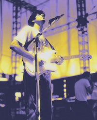 a man playing a guitar in front of a stage