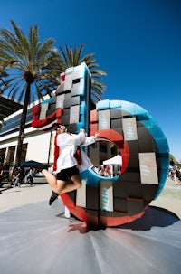 a group of people standing in front of a large sculpture of the letter d