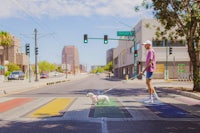 a man walking a dog across a rainbow colored crosswalk