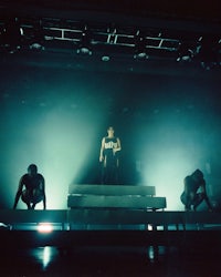 a group of people standing on a stage in front of a bright light