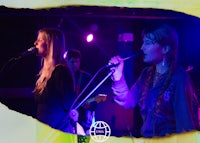 two women singing into microphones at a concert