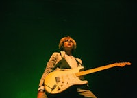 a man in a suit standing on a stage with a guitar