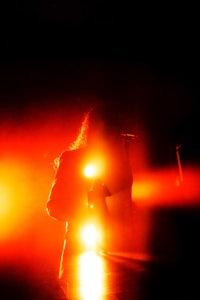 a person standing in front of a red light in a dark room