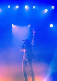 a man in a suit standing on stage with blue lights