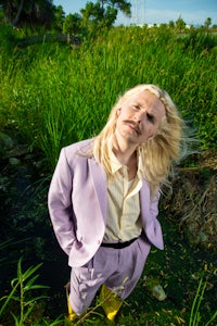 a man in a purple suit standing next to a pond