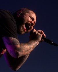 a man with tattoos singing into a microphone