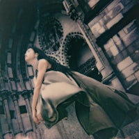 a woman in a long dress is posing in front of an ornate building