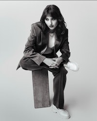 a black and white photo of a woman sitting on a wooden block