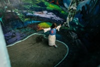 a girl in a white dress standing in front of a mural