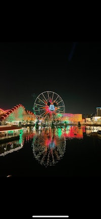 a ferris wheel is lit up at night in front of a building