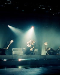 a group of people performing on stage in front of a spotlight