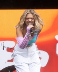 a woman in white pants singing into a microphone