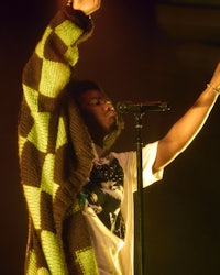 a man in a yellow and green sweater singing into a microphone