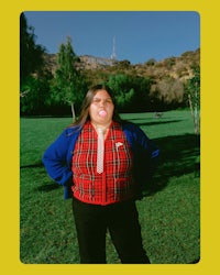 a woman in a plaid shirt standing in a park