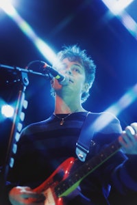 a man playing an electric guitar in front of a microphone