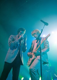 two men playing guitars on stage