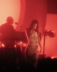 a woman in a dress on stage in front of a red light